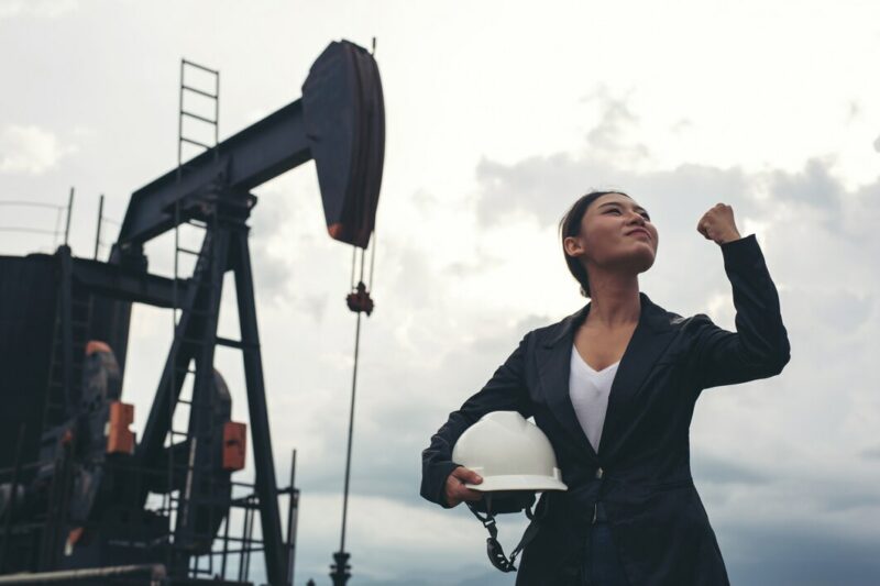 female engineer standing with working oil pumps with white sky 1150 19232 Cronos Asia