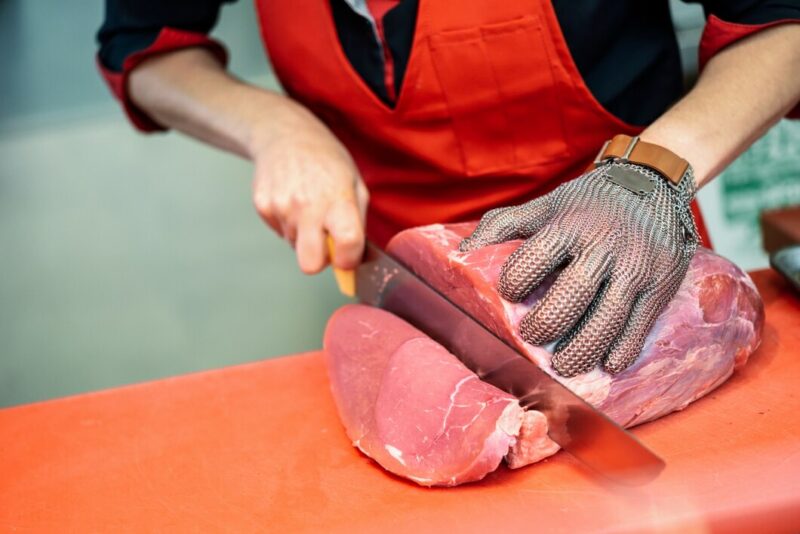 woman cutting fresh meat butcher shop with metal safety mesh glove 1139 1726 Cronos Asia