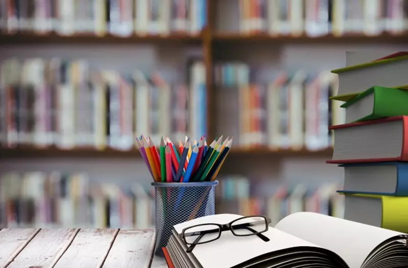 База Справедливого Казахстана ― качественное образование и воспитание патриотизма Стек книг в очках на деревянный стол - символизирующее образование в Казахстане